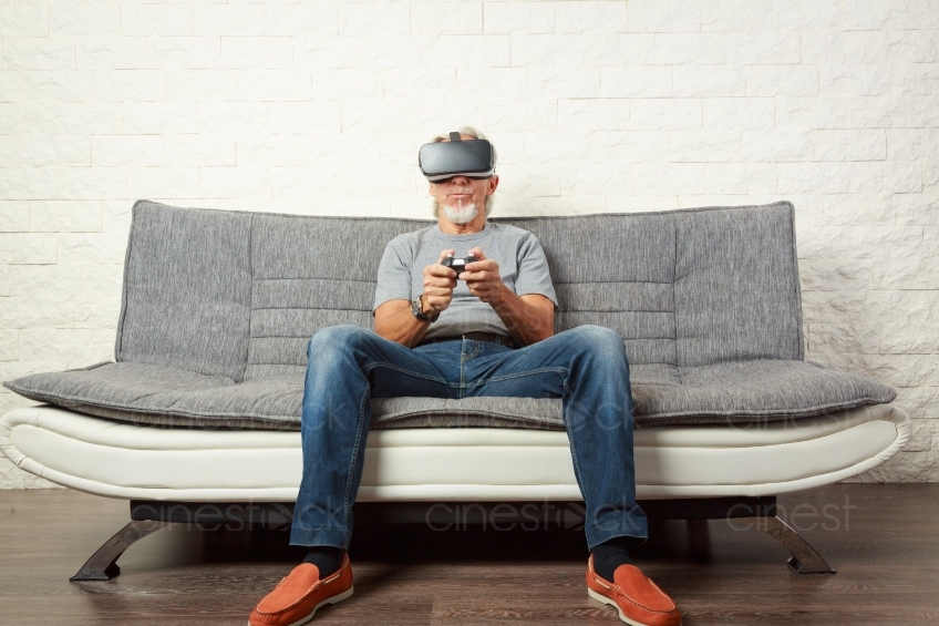 Mann auf Sofa spielt mit VR Brille und Steuerung 20160809-0329 